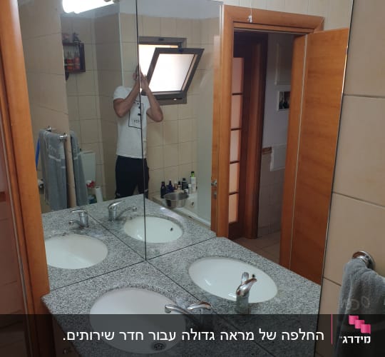 מראה גדולה מעל כיור בחדר אמבטיה